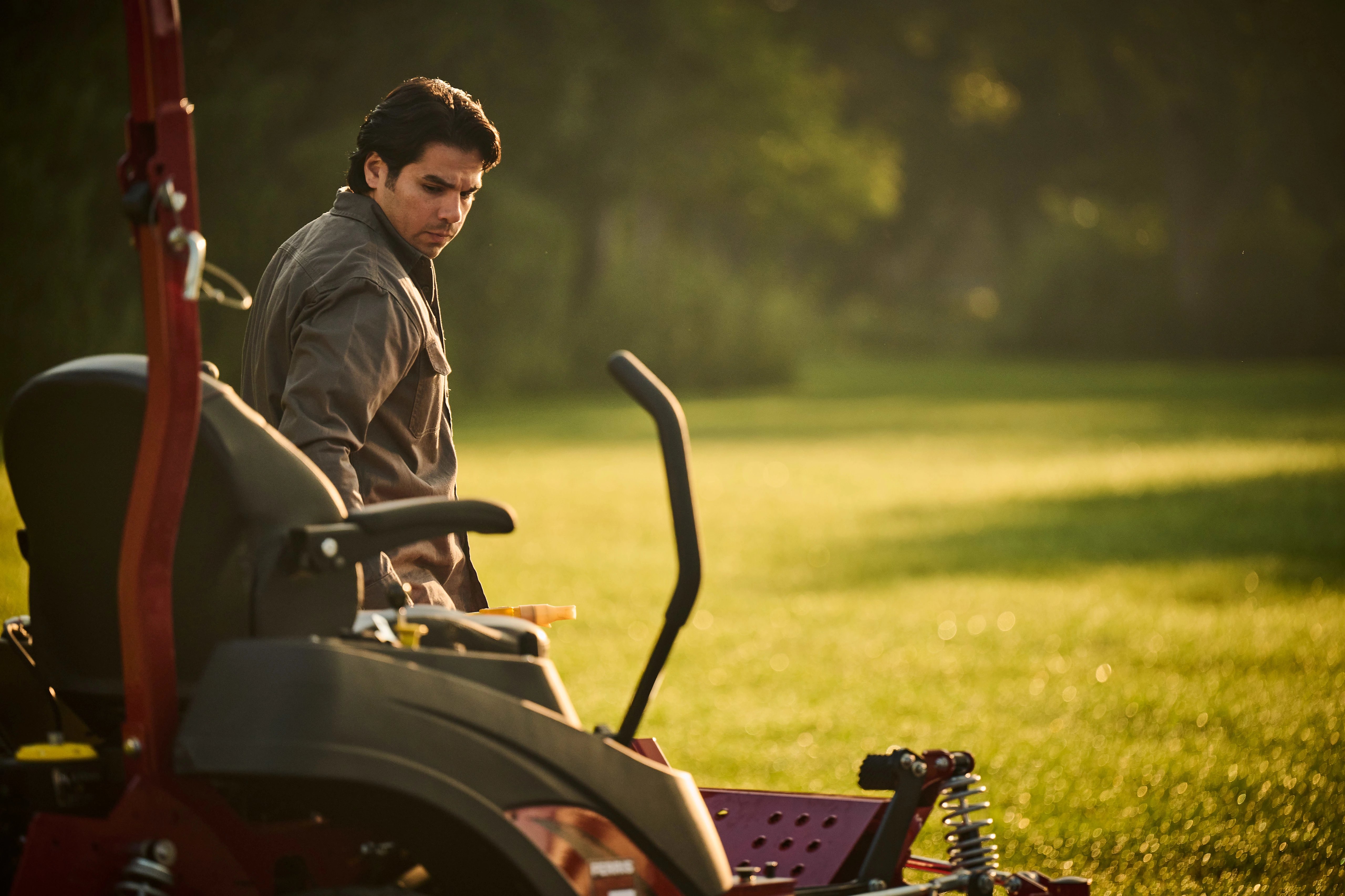 Landscaper standing proudly next to a Ferris zero-turn riding mower powered by a Briggs & Stratton CXi engine with Oil Xtend